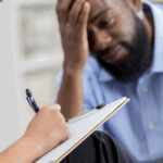 A man expresses stress about his relationship while speaking with a woman therapist in a supportive setting.